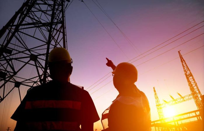 Two,Worker,Watching,The,Power,Tower,And,Substation,With,Sunset